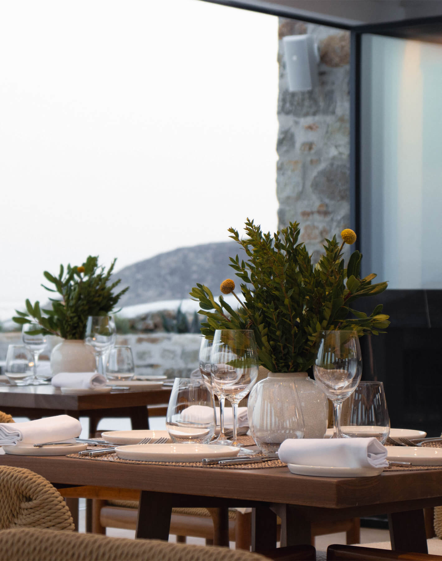 Dine in luxury with stunning Aegean Sea views at The Lounge, Cali Mykonos. Table set for dinner overlooking the azure waters, creating an unforgettable ambiance of elegance and tranquility.
