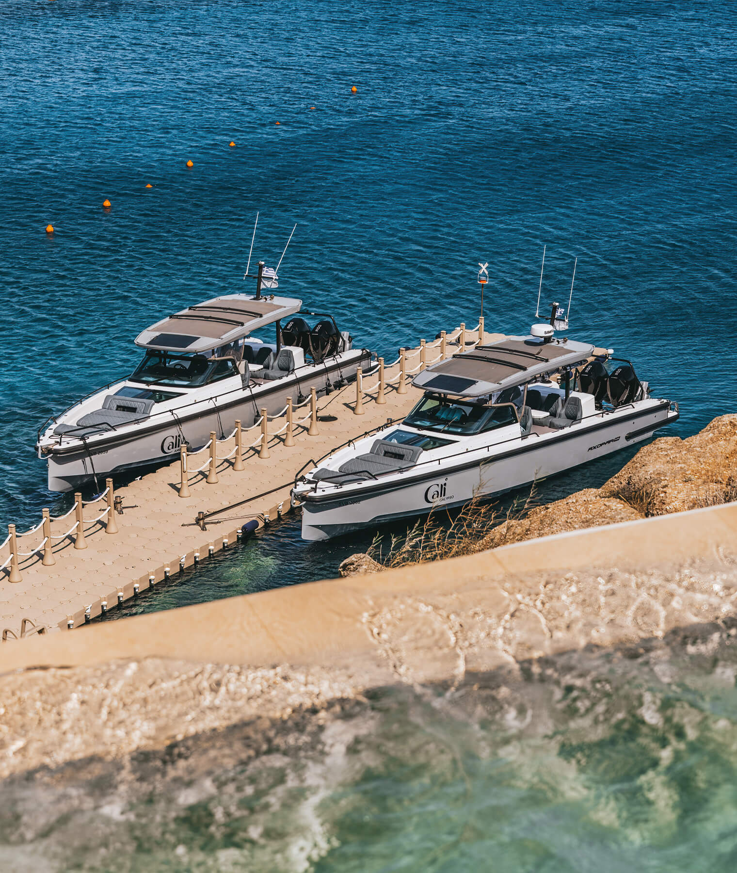 The Axopar 37 Sun-Top yacht anchored Cali's private dock, surrounded by crystal-clear waters and rugged coastal beauty.